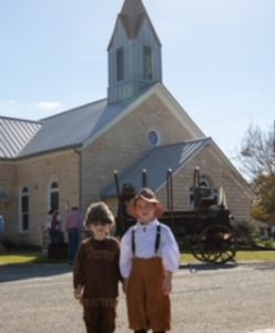 Photo of children in period costumes in front of historic chapel
