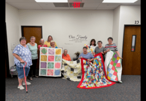 Quilters showing off quilts they made.