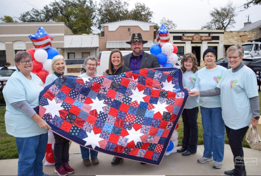 Quilters donating quilt at veteran's day celebration.
